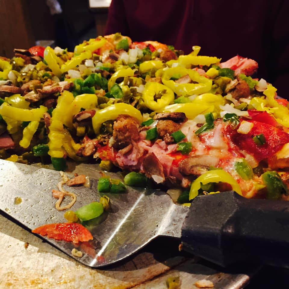 A fully loaded pizza with many toppings at Eddies